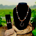 Copper goldstone beaded necklace with flower accents and a horseshoe pendant, displayed with matching drop earrings on a black bust.